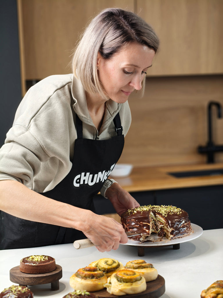 Woman in a kitchen wearing a 'Chunkz' apron, preparing a dessert.
