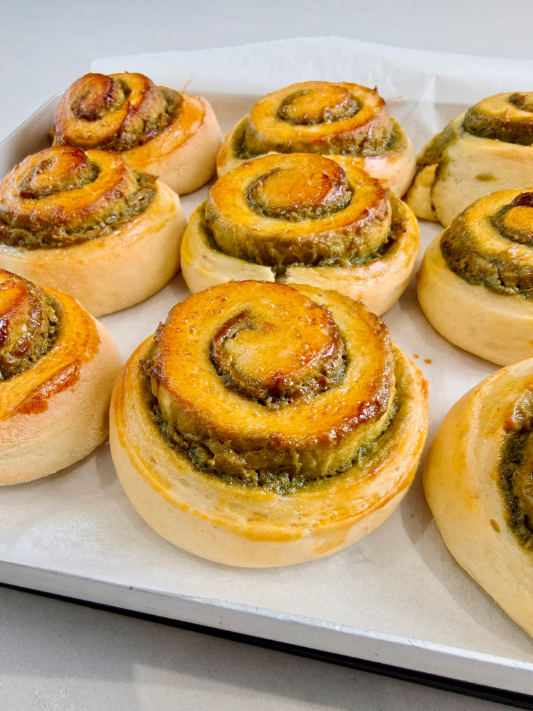Baked pastry rolls with green filling on a white tray